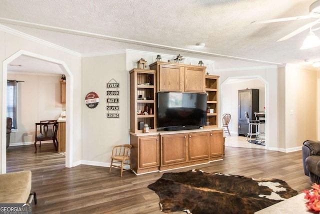 living room with ceiling fan, dark hardwood / wood-style floors, ornamental molding, and a textured ceiling