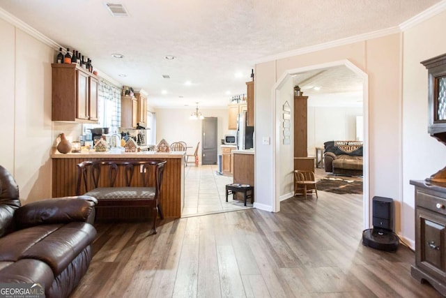 kitchen featuring hardwood / wood-style floors, a textured ceiling, stainless steel refrigerator, and crown molding