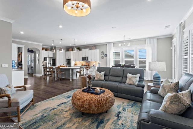 living room with dark hardwood / wood-style floors, crown molding, and an inviting chandelier