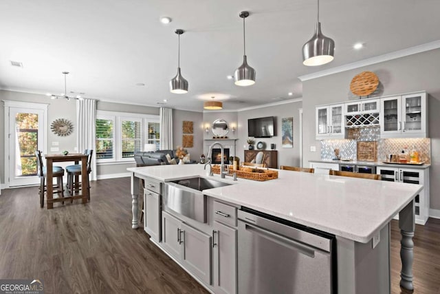 kitchen featuring stainless steel dishwasher, white cabinets, sink, and a center island with sink