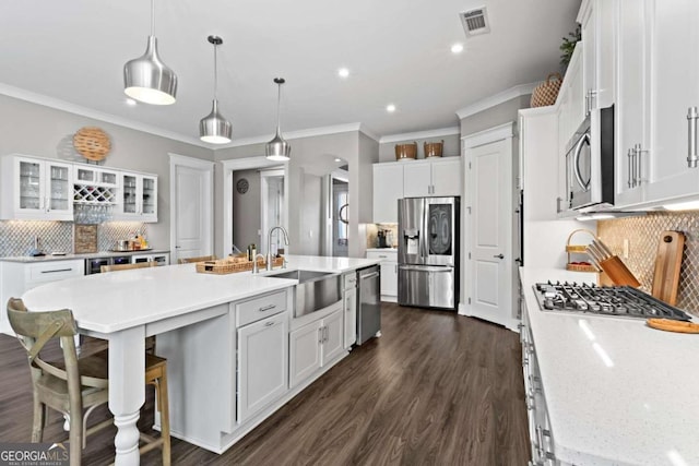 kitchen with decorative backsplash, white cabinetry, a kitchen island with sink, and appliances with stainless steel finishes