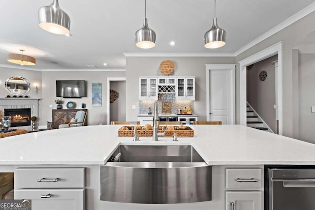 kitchen featuring a center island with sink, white cabinetry, crown molding, and sink