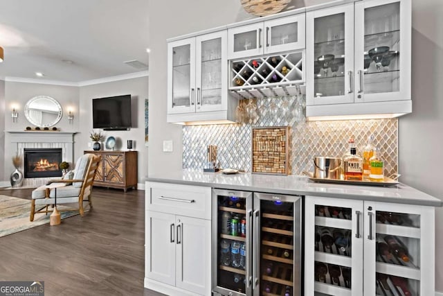 bar featuring beverage cooler, tasteful backsplash, a fireplace, white cabinets, and ornamental molding