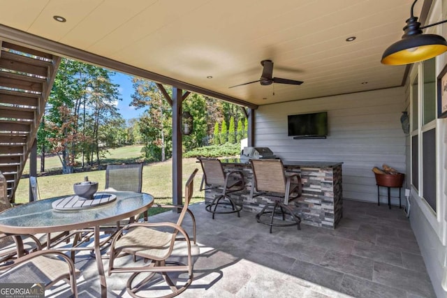 view of patio with exterior bar, a grill, ceiling fan, and exterior kitchen