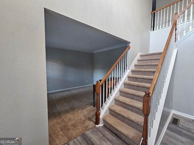 stairs with hardwood / wood-style floors and ornamental molding