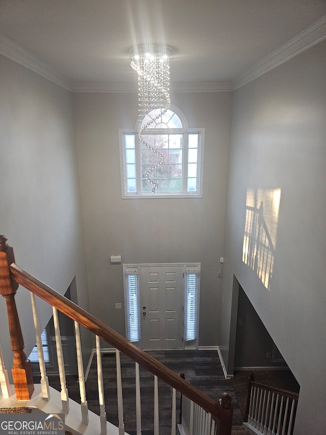 entryway with an inviting chandelier and crown molding