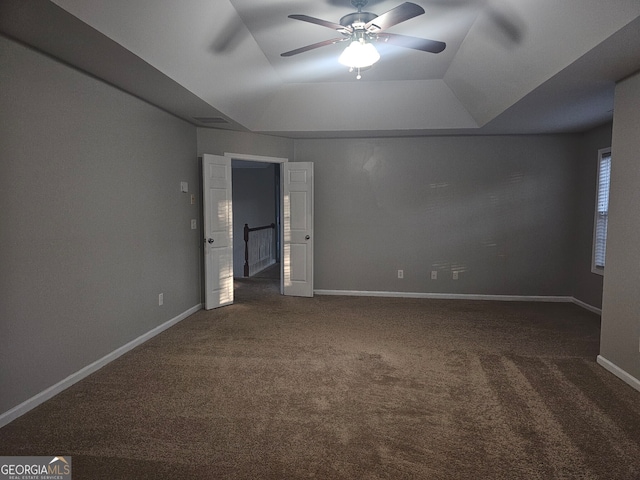 carpeted spare room with a raised ceiling and ceiling fan