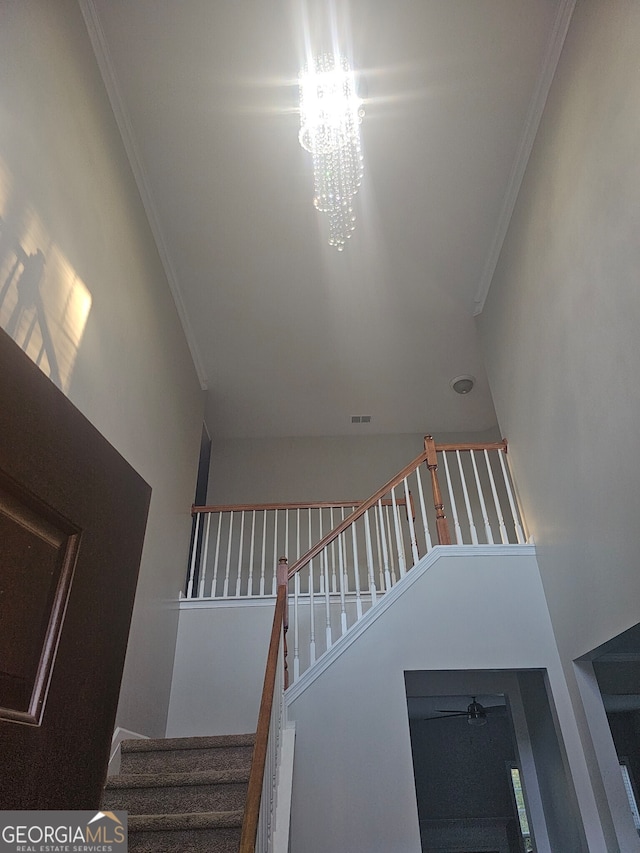 staircase with ornamental molding and a notable chandelier