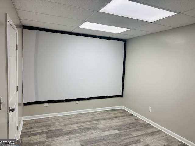 home theater room featuring hardwood / wood-style flooring and a drop ceiling