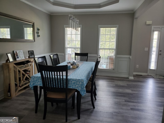 dining space with an inviting chandelier, crown molding, a wealth of natural light, and a raised ceiling