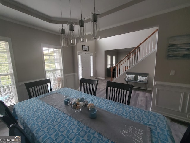 dining space with an inviting chandelier, crown molding, wood-type flooring, and a raised ceiling