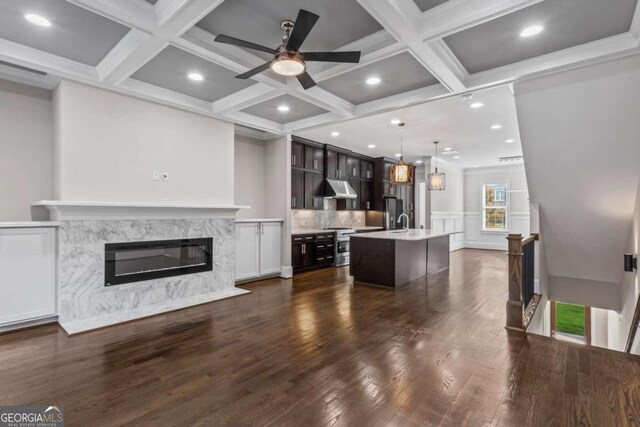 kitchen featuring dark brown cabinets, ceiling fan, pendant lighting, a premium fireplace, and an island with sink