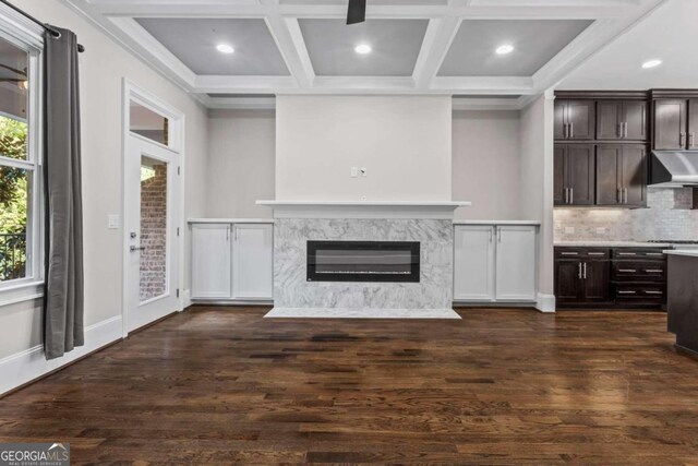 unfurnished living room featuring beamed ceiling, a premium fireplace, dark wood-type flooring, and coffered ceiling