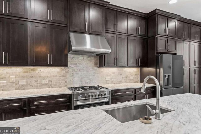 kitchen with dark brown cabinetry, light stone countertops, sink, stainless steel appliances, and tasteful backsplash