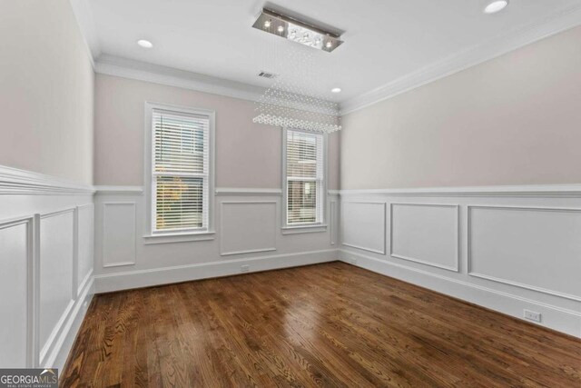 empty room with a chandelier, dark hardwood / wood-style floors, and crown molding