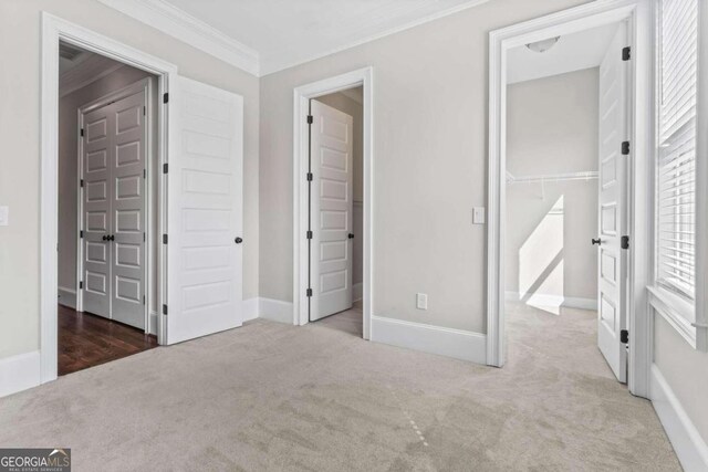 unfurnished bedroom featuring crown molding, light carpet, and a closet