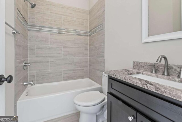 full bathroom featuring toilet, vanity, and tiled shower / bath