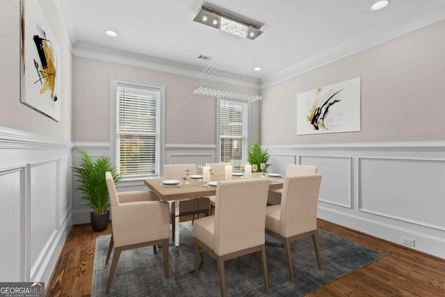 dining space featuring dark hardwood / wood-style flooring, ornamental molding, and a notable chandelier