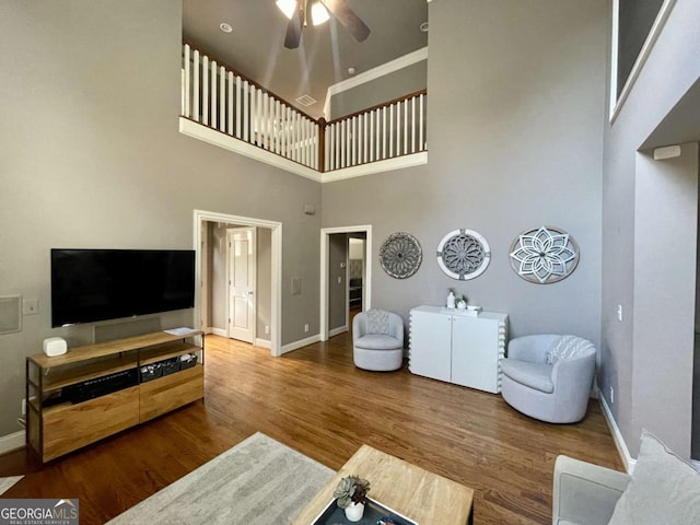 living room featuring a high ceiling, hardwood / wood-style flooring, and ceiling fan