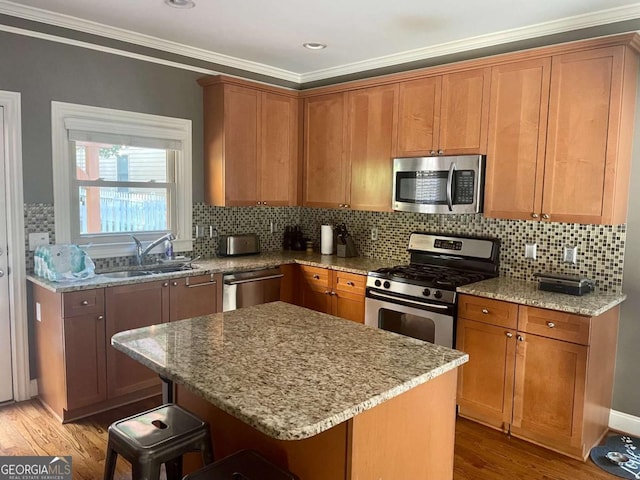 kitchen with a center island, a kitchen breakfast bar, sink, appliances with stainless steel finishes, and light hardwood / wood-style floors