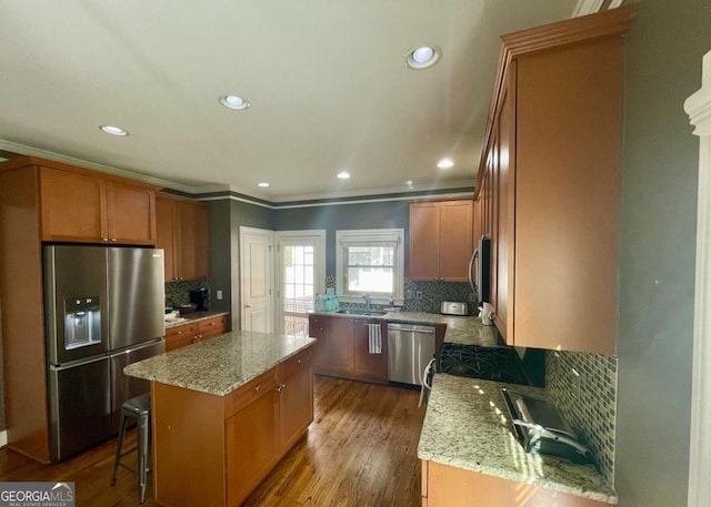 kitchen with a center island, sink, dark hardwood / wood-style floors, light stone counters, and stainless steel appliances