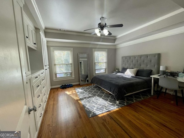 bedroom featuring dark hardwood / wood-style flooring, a tray ceiling, ceiling fan, and crown molding