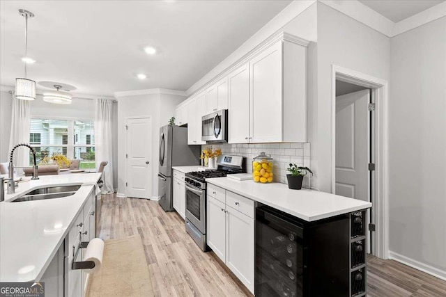 kitchen with pendant lighting, white cabinets, sink, light hardwood / wood-style flooring, and stainless steel appliances