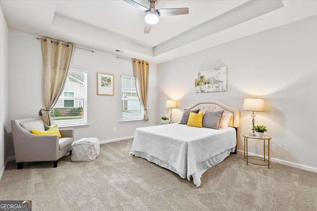 bedroom with carpet flooring, a tray ceiling, and ceiling fan