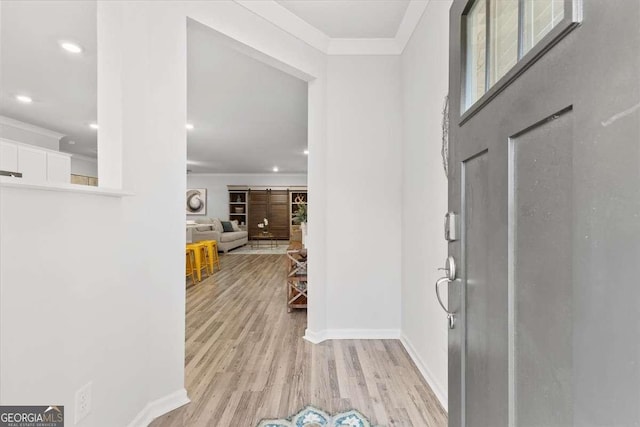 foyer entrance featuring crown molding and light hardwood / wood-style flooring