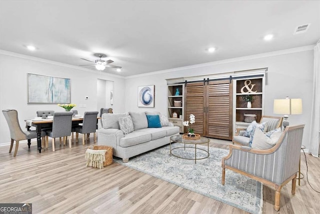 living room featuring ceiling fan, built in features, light hardwood / wood-style floors, and ornamental molding