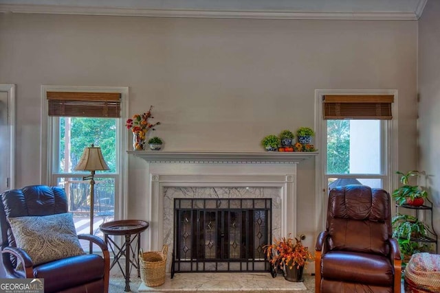 sitting room featuring a high end fireplace, a wealth of natural light, and crown molding