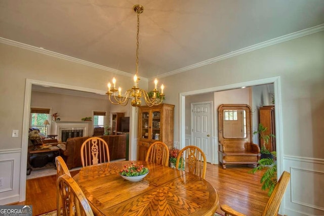 dining area featuring hardwood / wood-style floors, an inviting chandelier, and crown molding