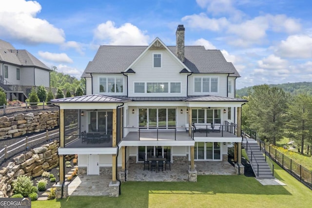 rear view of property with a lawn, a sunroom, and a patio area