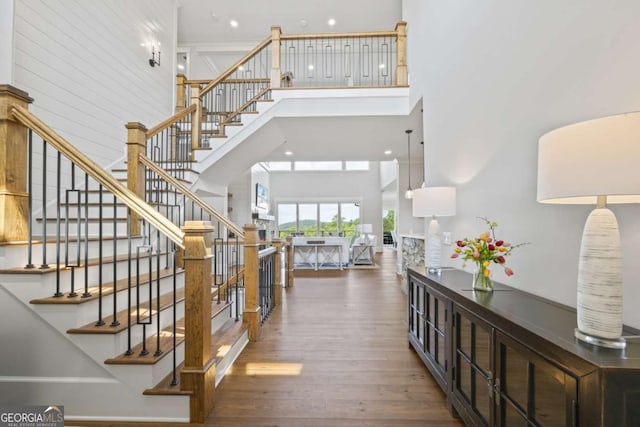 stairway featuring wood-type flooring and a towering ceiling