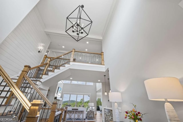 interior space featuring a towering ceiling, a chandelier, and ornamental molding