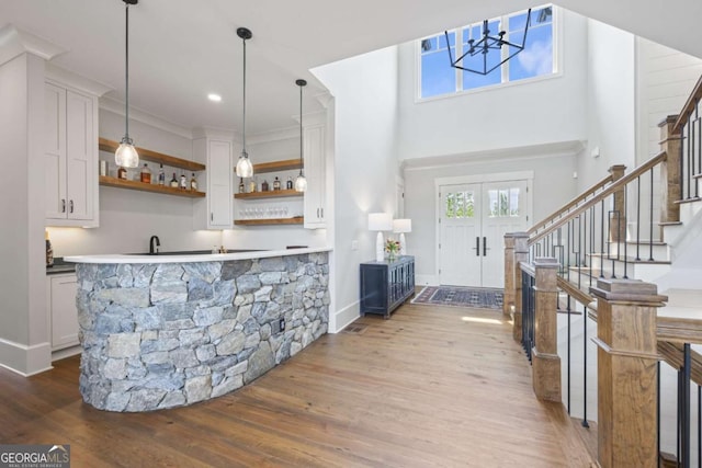 bar featuring white cabinets, pendant lighting, crown molding, and hardwood / wood-style floors