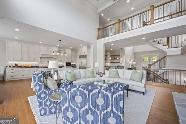 living room featuring light wood-type flooring, crown molding, and a high ceiling