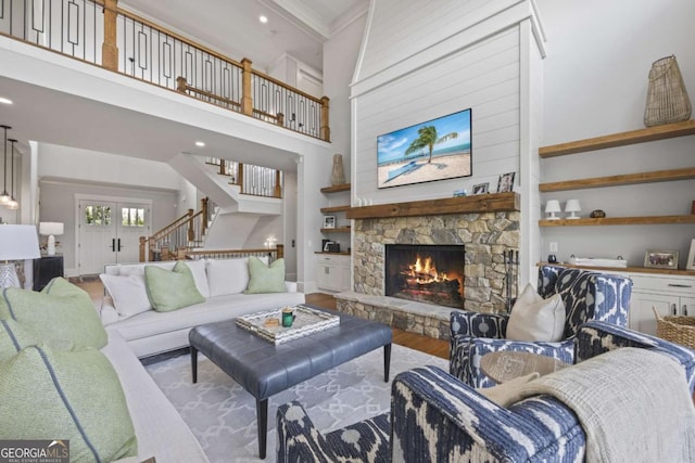 living room featuring a towering ceiling, light hardwood / wood-style flooring, and a stone fireplace