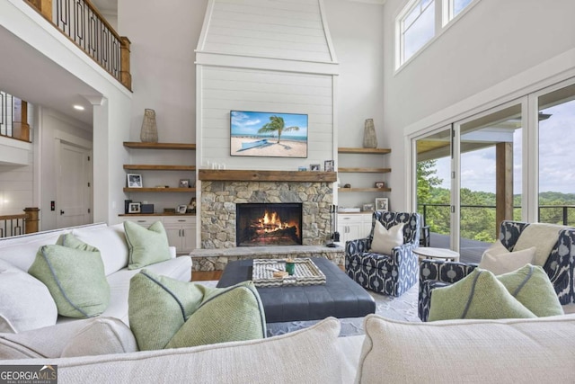 living room with a stone fireplace, a healthy amount of sunlight, and a high ceiling