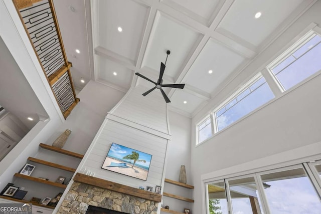 interior details featuring ceiling fan, a fireplace, beamed ceiling, and coffered ceiling