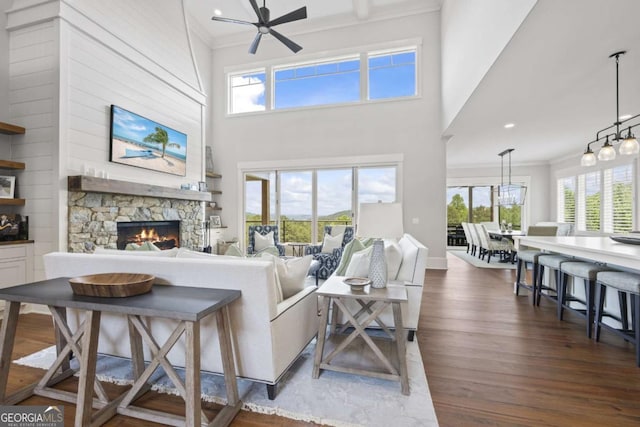 living room featuring a fireplace, dark hardwood / wood-style flooring, ceiling fan, and ornamental molding