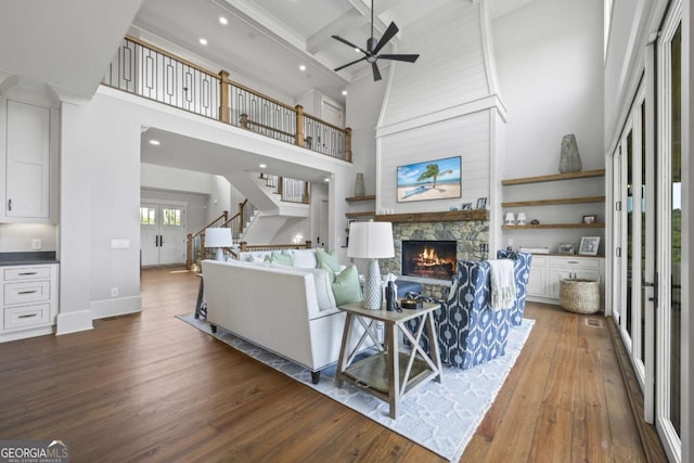 living room featuring ceiling fan, coffered ceiling, beamed ceiling, wood-type flooring, and a fireplace