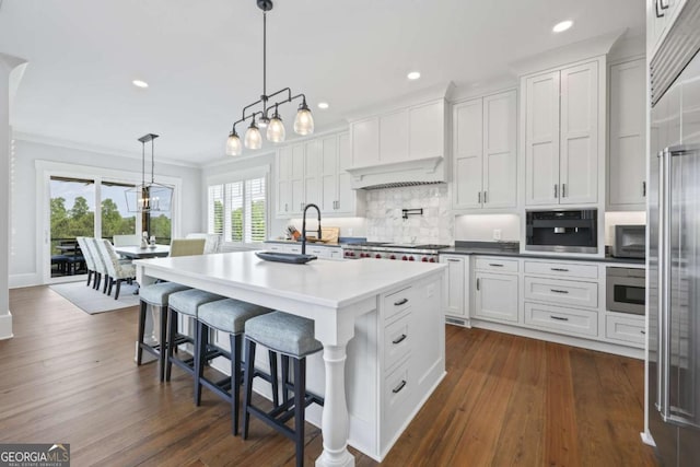 kitchen with a center island with sink, white cabinets, dark wood-type flooring, and decorative light fixtures