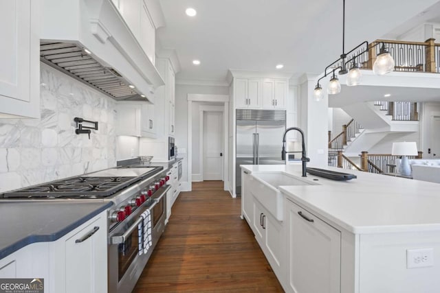 kitchen featuring premium range hood, tasteful backsplash, decorative light fixtures, range with two ovens, and white cabinets