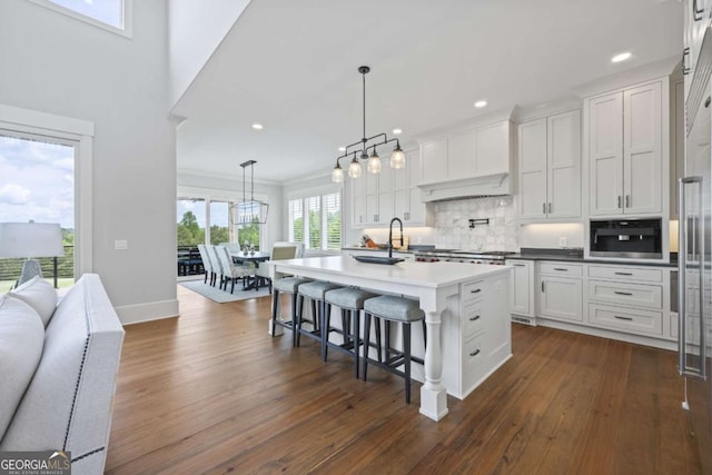 kitchen with white cabinets, pendant lighting, an island with sink, and built in microwave