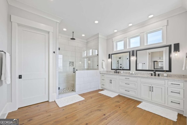 bathroom featuring hardwood / wood-style floors, vanity, a shower with shower door, and ornamental molding