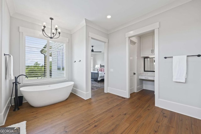 bathroom with a bathtub, crown molding, wood-type flooring, and ceiling fan with notable chandelier