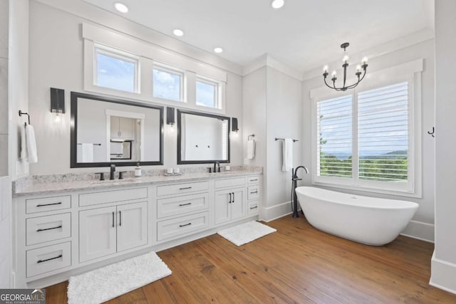 bathroom with a tub, a notable chandelier, crown molding, hardwood / wood-style floors, and vanity