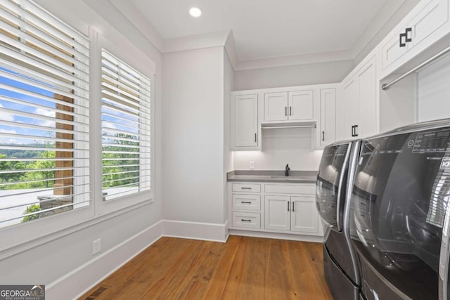 laundry room with sink, cabinets, dark hardwood / wood-style floors, washer and dryer, and ornamental molding