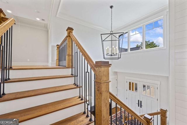 stairs with ornamental molding and an inviting chandelier